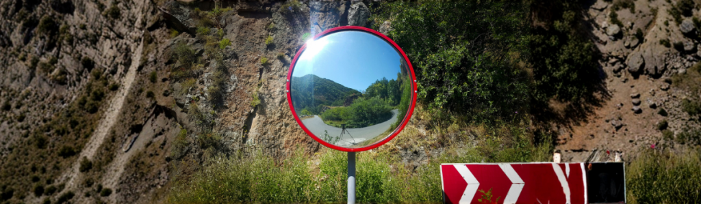 Miroir routier installé sur une route pour améliorer la visibilité et la sécurité des conducteurs.