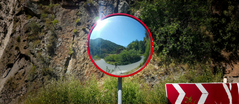Miroir routier installé sur une route pour améliorer la visibilité et la sécurité des conducteurs.